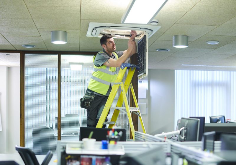 Maintenance person fixing a ceiling air conditioning unit