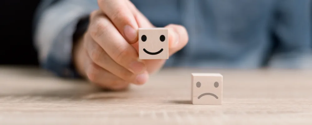 Hand holding a cube with a happy face on for client care